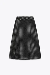 Falda midi negra con estampado de lunares blancos, de tiro alto y corte evasé.