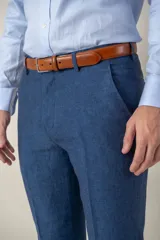 Pantalón de vestir azul marino, de corte recto, confeccionado en lino. Se ajusta a la cintura con cinturón de cuero marrón.