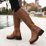 Bota de caña alta color marrón, confeccionada en cuero vacuno. Tiene suela de goma sport artesanal, cierre YKK del lado interno y horma de punta redonda.