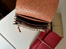 Billetera tipo sobre de cuero negro con cierre de elástico, separaciones internas y bolsillo con cierre para monedas.