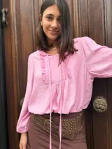 Blusa rosa de mangas largas con puños elásticos, escote en V con volados y lazos.
