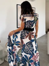 Vestido largo con estampado de hojas en tonos marrones, amarillos y verdes. Tiene escote cruzado y cinturón de la misma tela.