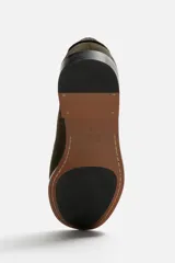 Mocasín color marrón de cuero con acabado serraje, antifaz, horma redonda y suela con ligero tacón.