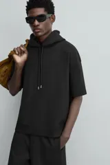 Sudadera negra de algodón con capucha ajustable y mangas cortas.