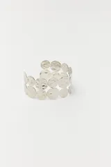 Pulsera rígida plateada con diseño de círculos texturizados.