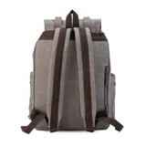 Mochila de tela canvas color verde oliva con tapa y detalles en símil cuero marrón. Cierre superior marinero, bolsillos internos, externos frontal, laterales y trasero con cierre. Asas rígidas, correas ajustables y espacio para laptop de 15".