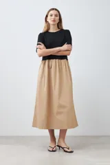 Vestido midi de corte recto, con top negro de mangas cortas y falda color beige.
