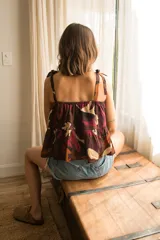 Top corto de algodón estampado con motivos florales en tonos marrón, naranja y fucsia. Tiene breteles finos con lazos ajustables y elástico en la espalda.