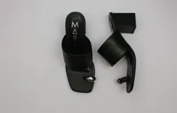 Sandalias negras con taco cuadrado y tira ancha sobre el empeine. Presentan una tira fina que separa el dedo gordo del resto y un aplique metálico plateado.