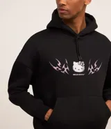 Buzo negro con capucha y cordón de ajuste, con estampa frontal de Hello Kitty y detalles tribales en color rosa. Tiene bolsillo tipo canguro y puños ajustados.