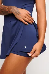 Vestido deportivo color verde con logo bordado en blanco en el pecho. Diseño sin mangas, con cuello mao y cierre parcial con botones. Falda con corte evasé y short interno.