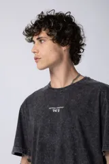 Remera negra con efecto gastado, corte holgado y estampa frontal con la frase 'Astral Energy' en blanco.