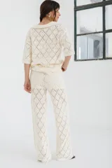 Pantalón de tejido de punto color crema, de tiro alto y pierna ancha, con diseño calado de rombos.