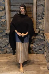 Ruana color crudo tejida a mano en punto arroz con lana merino. Presenta flecos en el borde inferior.