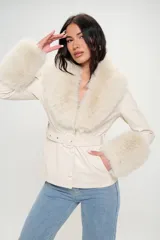 Blazer color crema con cuello y puños de piel sintética color crema. Tiene corte entallado, cierre frontal con botones y cinturón con hebilla.