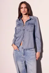 Camisa de denim de corte al cuerpo, con dos bolsillos frontales y cierre de botones.