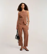 Pantalón de vestir color marrón, de corte recto y tiro alto, con cierre frontal y bolsillos delanteros.