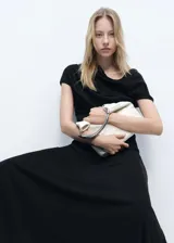 Blusa negra con cuello asimétrico y diseño drapeado, de manga corta y corte recto.