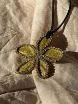 Collar con dije de flor azul brillante con borde de strass plateado y cordón negro.