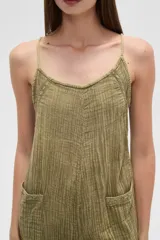 Mono de algodón negro, estilo lencero, con tirantes finos, escote en V y bolsillos frontales. El calce es holgado y presenta un cordón ajustable en la cintura.