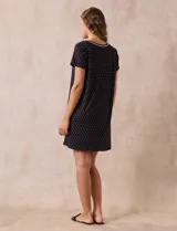 Camisón corto negro con lunares blancos, de tejido suave y escote redondo con detalle plisado y moño blanco.