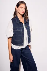 Chaleco de jean azul oscuro con cuello, bolsillos frontales y cierre con botones dorados. Corte al cuerpo.