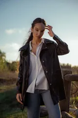 Chaqueta de cuero ovino italiano color negro, con cuello clásico, cierre frontal con botones a presión, bolsillos laterales con solapa y costuras en contraste color naranja.