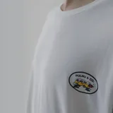 Remera blanca de algodón con estampa en la espalda de una combi amarilla con llamas saliendo del escape, dentro de un óvalo con el texto "Pulau & Co.".