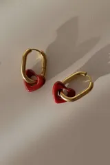 Aros colgantes con forma de argolla dorada y dije de corazón rojo.