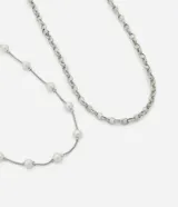 Kit de dos collares plateados de la marca VIKO. El conjunto incluye un collar de cadena con eslabones circulares y un segundo collar de cadena fina con perlas blancas distribuidas de forma espaciada. Ambas piezas cuentan con cierre de mosquetón y cadena de alargue para ajustar el largo.