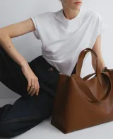 Bolso tipo tote grande color marrón, con doble asa de mano y correa larga extraíble. Interior con dos compartimentos y bolsillo central con cierre.