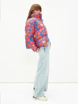 Campera puffer corta con estampado abstracto en tonos verde, naranja y azul. Tiene cuello alto, cierre frontal con cremallera y bolsillos laterales.