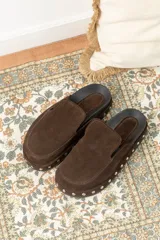 Zuecos marrones de gamuza con plataforma forrada en cuero y tachas plateadas alrededor de la suela.