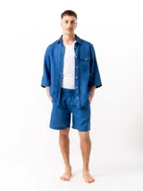 Camisa azul de lino con mangas 3/4, un bolsillo en el lado izquierdo y un pliegue en la espalda.
