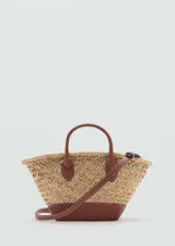 Bolso tipo canasta de paja con base y asas de cuero marrón. Tiene correa larga desmontable para usar como bandolera.