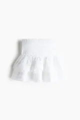 Minifalda blanca de algodón con cintura elastizada y volados escalonados con inserciones de encaje.