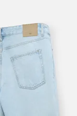 Pantalón de jean celeste de corte slim fit y tapered, con cinco bolsillos, efecto lavado y cierre frontal con cremallera y botón.