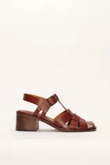 Sandalias plateadas de cuero con tiras entrecruzadas y hebilla lateral. Taco de madera de 6 cm.