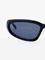 Lentes de sol negros con forma ovalada y patillas gruesas.