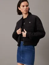 Campera bomber acolchada negra Calvin Klein, con logo bordado en el pecho y el puño. Confeccionada con poliéster reciclado, cuello, puños y bajo de canalé, cierre de cremallera, bolsillos con botón de presión en la cintura y forro ligeramente acolchado.