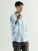 Camisa de manga larga color verde oliva, confeccionada en algodón. Tiene corte clásico, bolsillo en el lado izquierdo del pecho y cierre con botones.