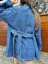 Campera denim azul con corte trench, bolsillos frontales y cierre con botones.