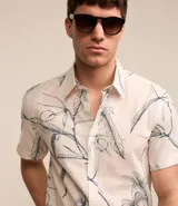 Camisa de hombre confeccionada en voil color crudo con estampa floral estilo outline en azul. Tiene cuello inglés, abotonado delantero y manga corta.