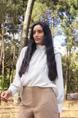 Blusa blanca de cuello alto con detalles en los puños y mangas largas abullonadas.