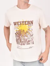 Remera color crudo con estampa frontal de estilo western con texto y paisaje desértico.