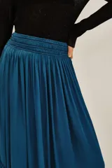 Falda larga de corte fluido en color azul petróleo, con cintura ancha elástica tipo smock y un volado amplio en el ruedo.