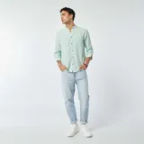 Camisa celeste claro de lino con cuello mao, manga larga con puños abotonados y bolsillo de parche en el pecho.