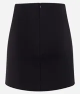 Minifalda negra de punto roma con cinturón fino con hebillas metálicas.