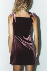 Vestido corto de terciopelo color borgoña, con escote cuadrado y tirantes finos con lazos. Cierre trasero con cremallera oculta.