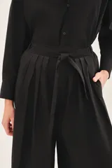 Mono negro con corte palazzo, mangas largas y lazo en la cintura.